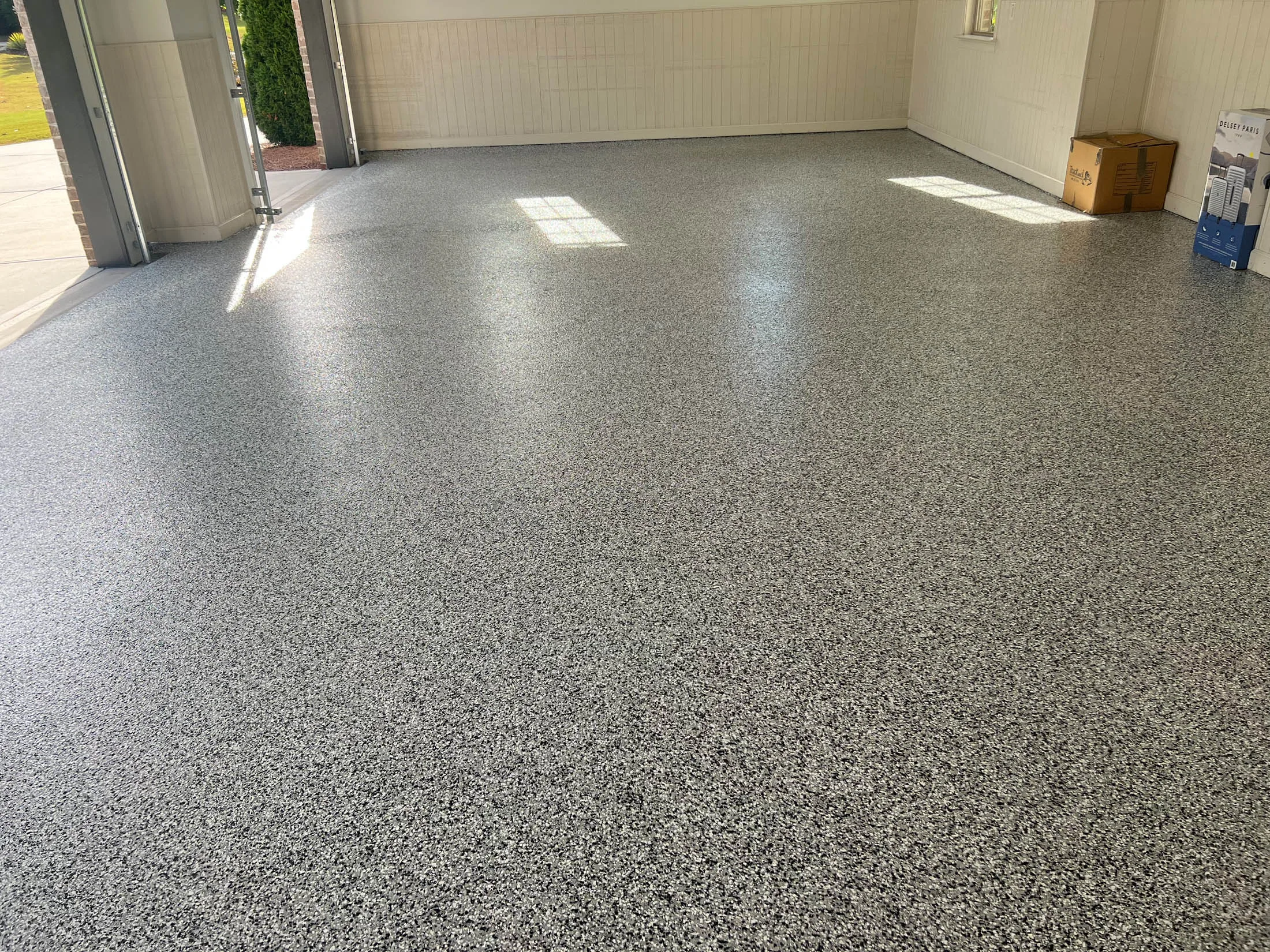 Seamless, high-performance epoxy garage floor coating in a well-lit space, showcasing a smooth, speckled finish, emphasizing durability and aesthetic appeal for residential applications.