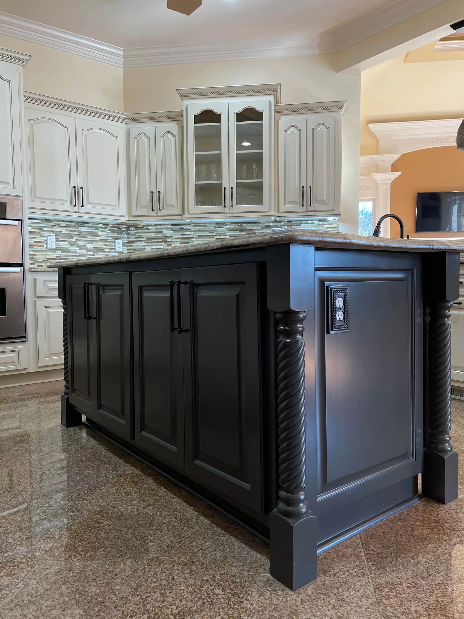 Kitchen island with black cabinetry and decorative rope detailing, showcasing a modern design in a bright kitchen setting, emphasizing cabinet refinishing and painting services offered by Arreguin's Paint Contractor.