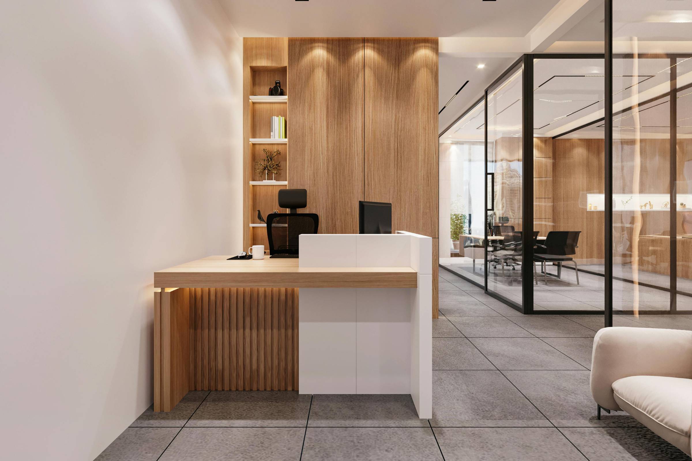 Modern office reception area with a wooden and white desk, office chair, computer, built-in shelves, and fresh new construction painting; a glass-walled meeting room is visible in the background.