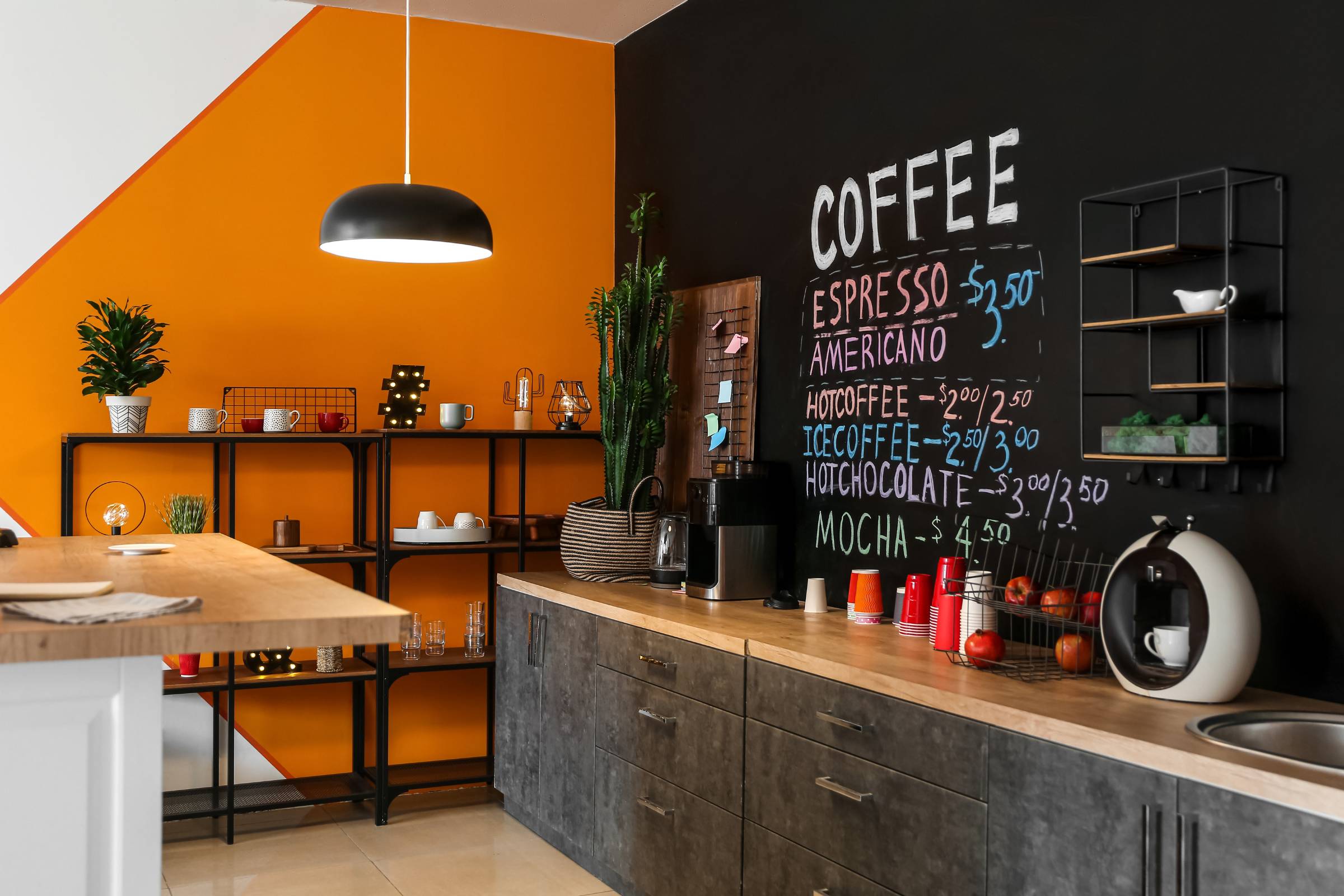 Modern kitchen corner with orange and black walls featuring fresh New Construction Painting, a chalkboard coffee menu, open shelving, countertop appliances, and a hanging light fixture.