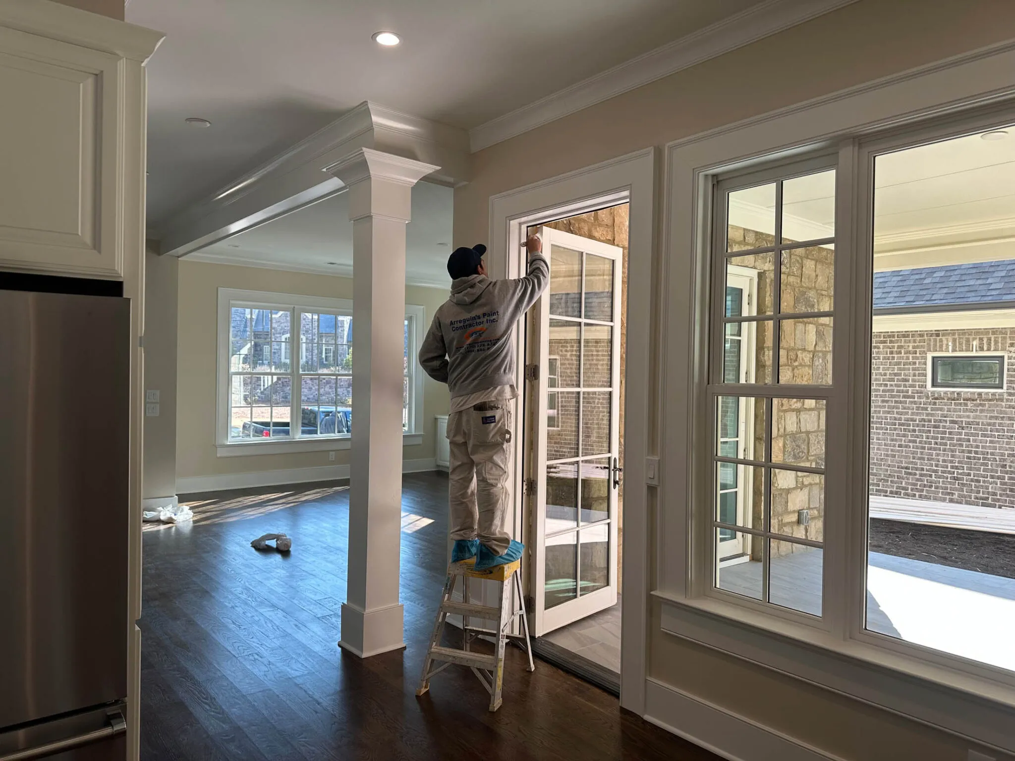 Arrogante Paint Contractor on ladder painting new home's French doors